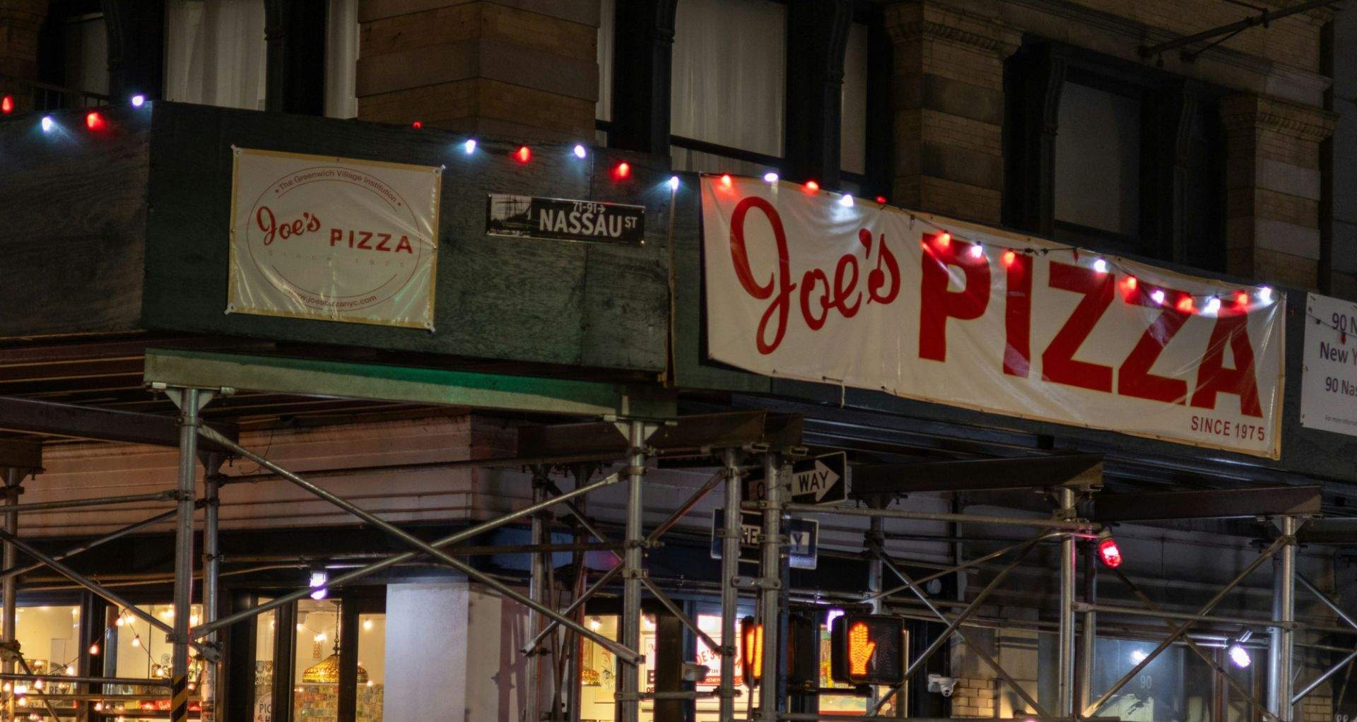 Joe's PIZZA라고 적힌 간판과 건물, 길 이름 표지판이 있는 도시 장면