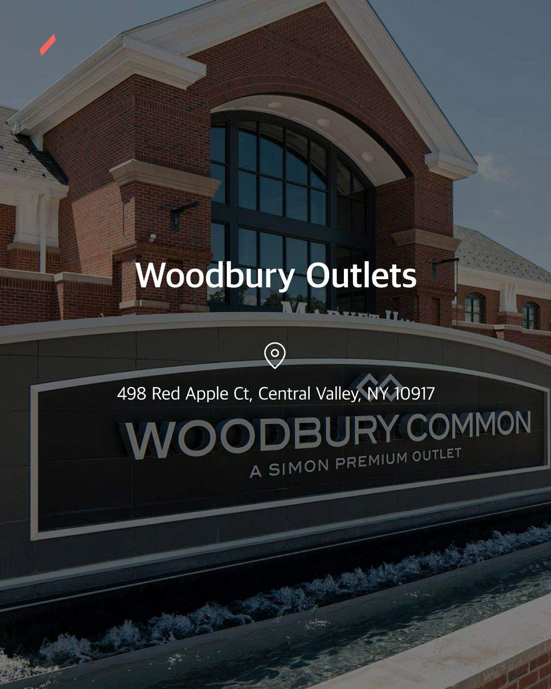 브릭 건물 외벽에 Woodbury Outlets 간판이 설치된 상업 시설의 모습