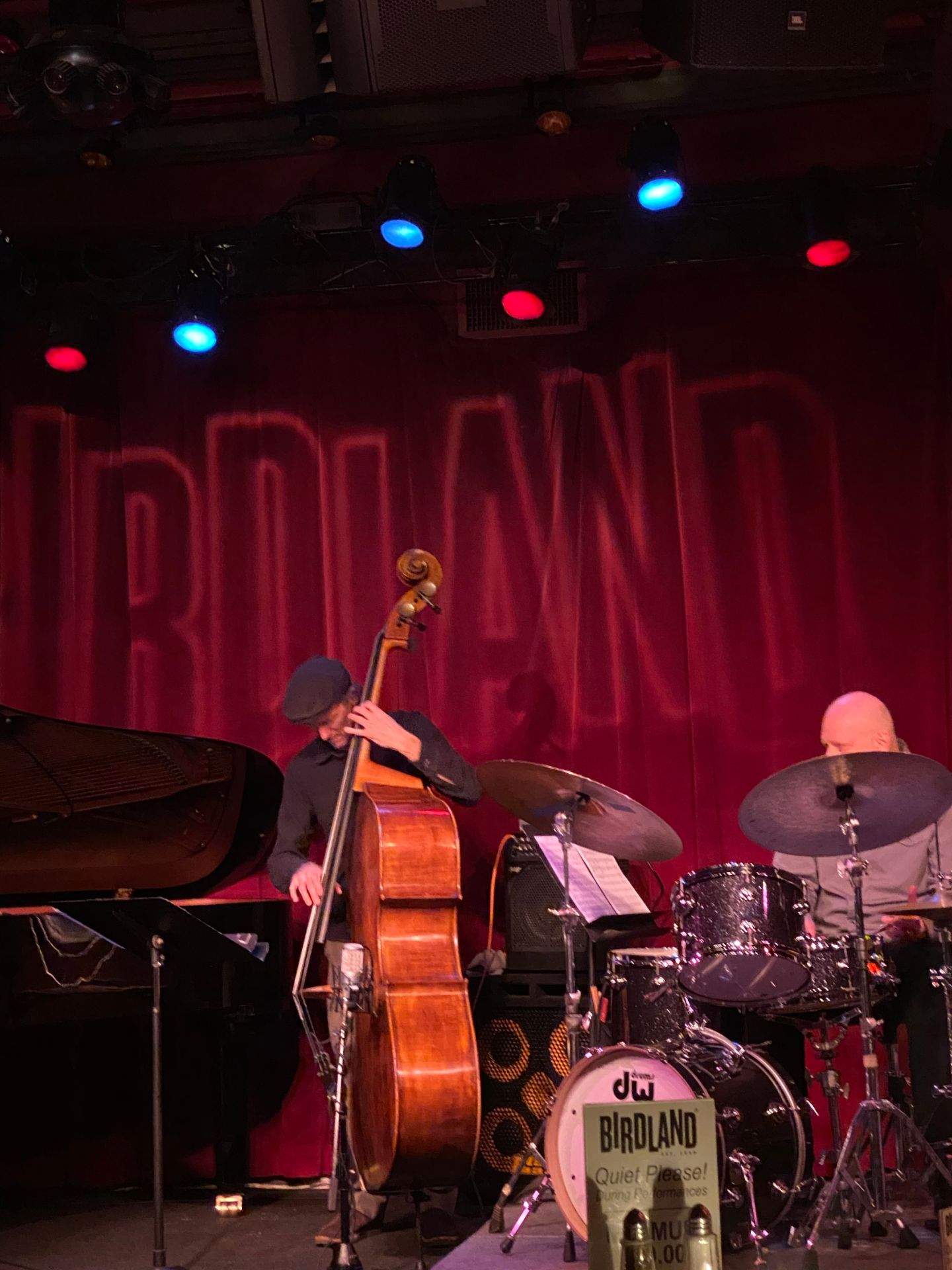 BIRDLAND 무대 위 피아노, 베이스 기타, 드럼 세트가 있는 공연 장면