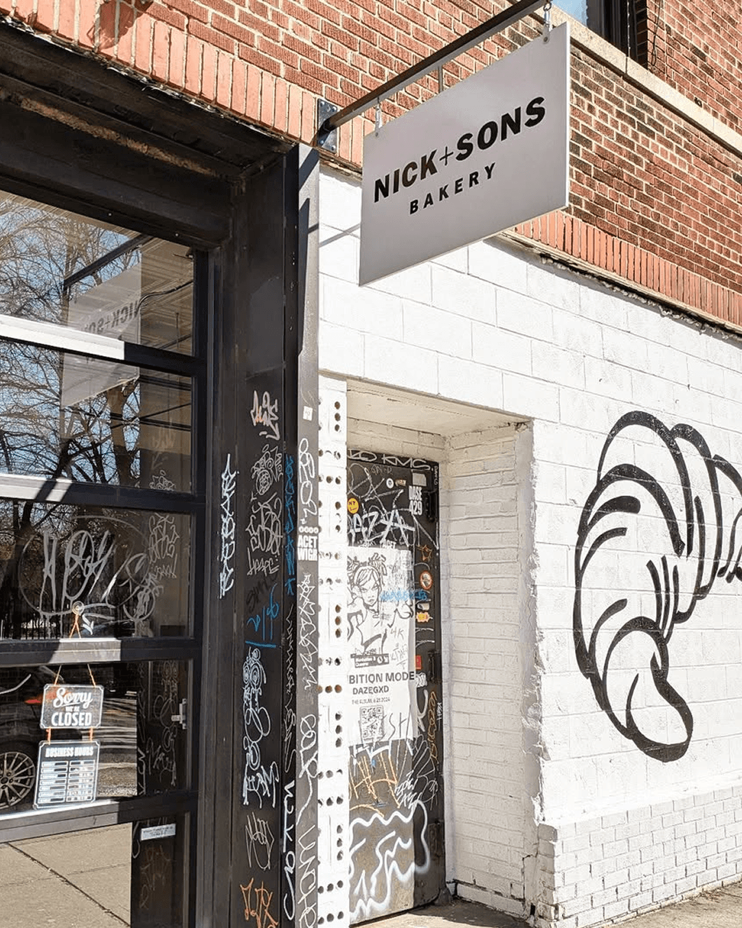 NICK+SONS BAKERY라는 문구가 적힌 유리문이 있는 벽돌 건물 베이커리 상점의 외부 모습