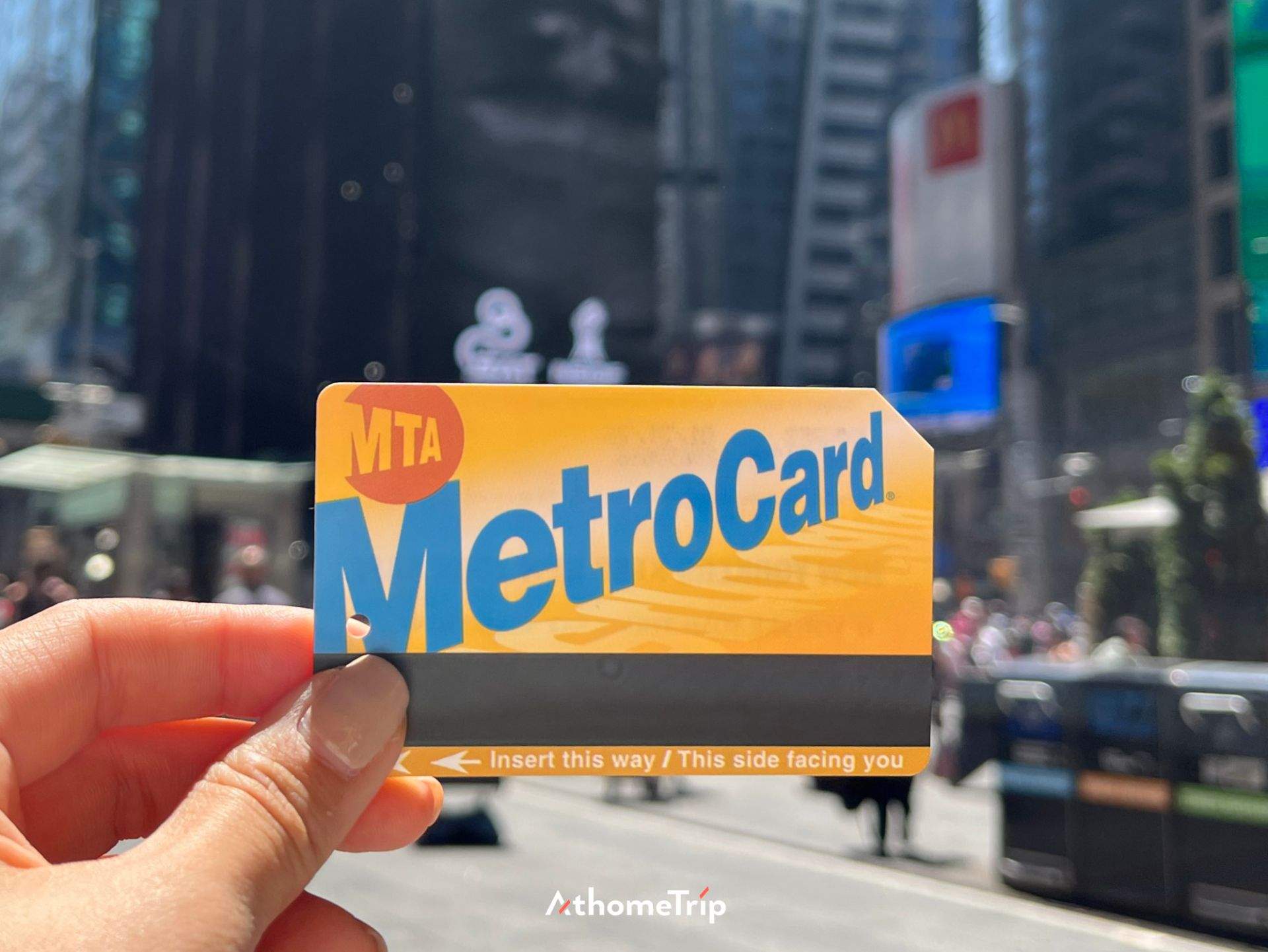사람이 손에 들고 있는 MTA MetroCard와 배경의 건물