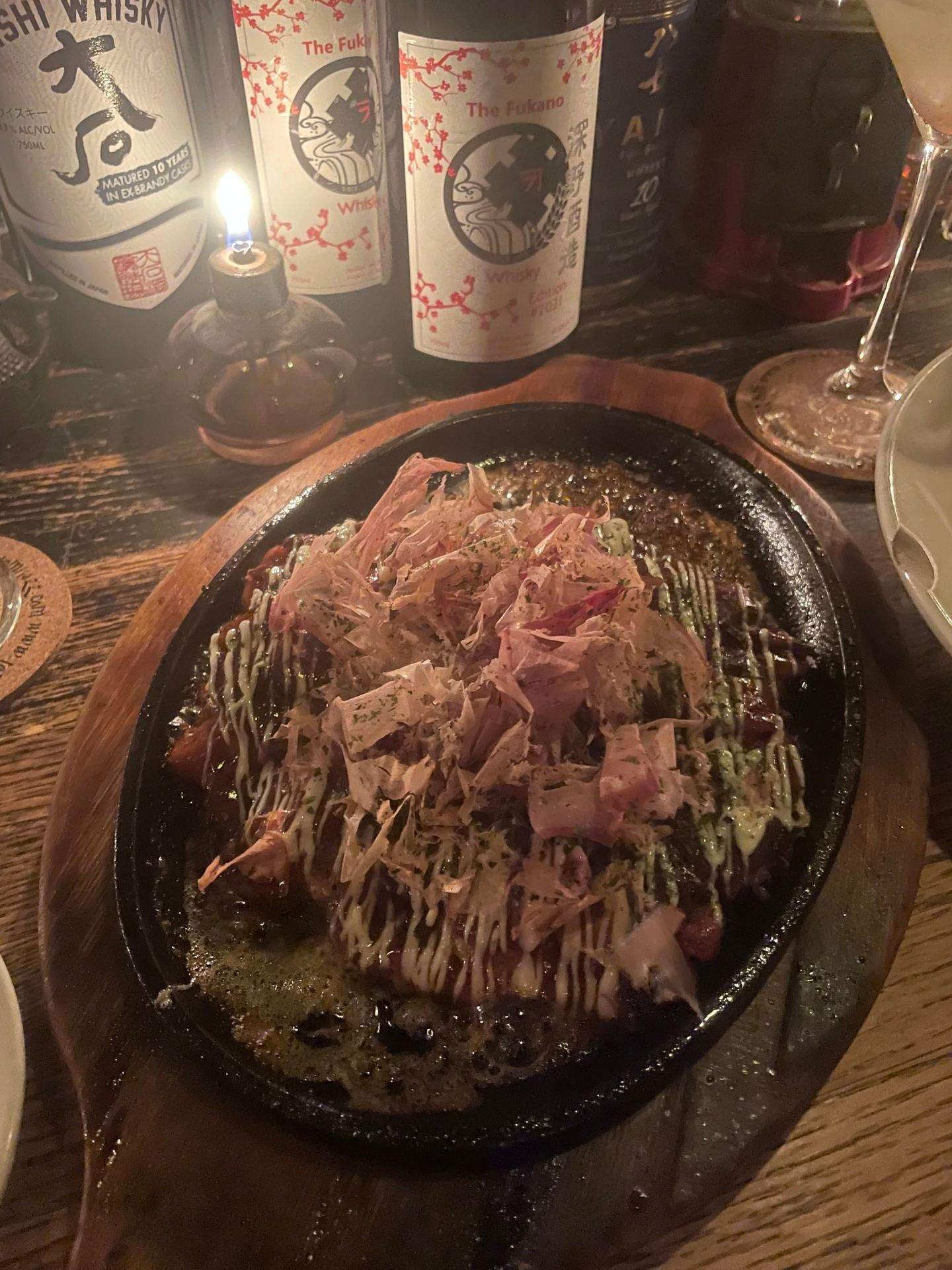 검은색 팬 안에 담긴 고기와 소스, 주변의 술병
