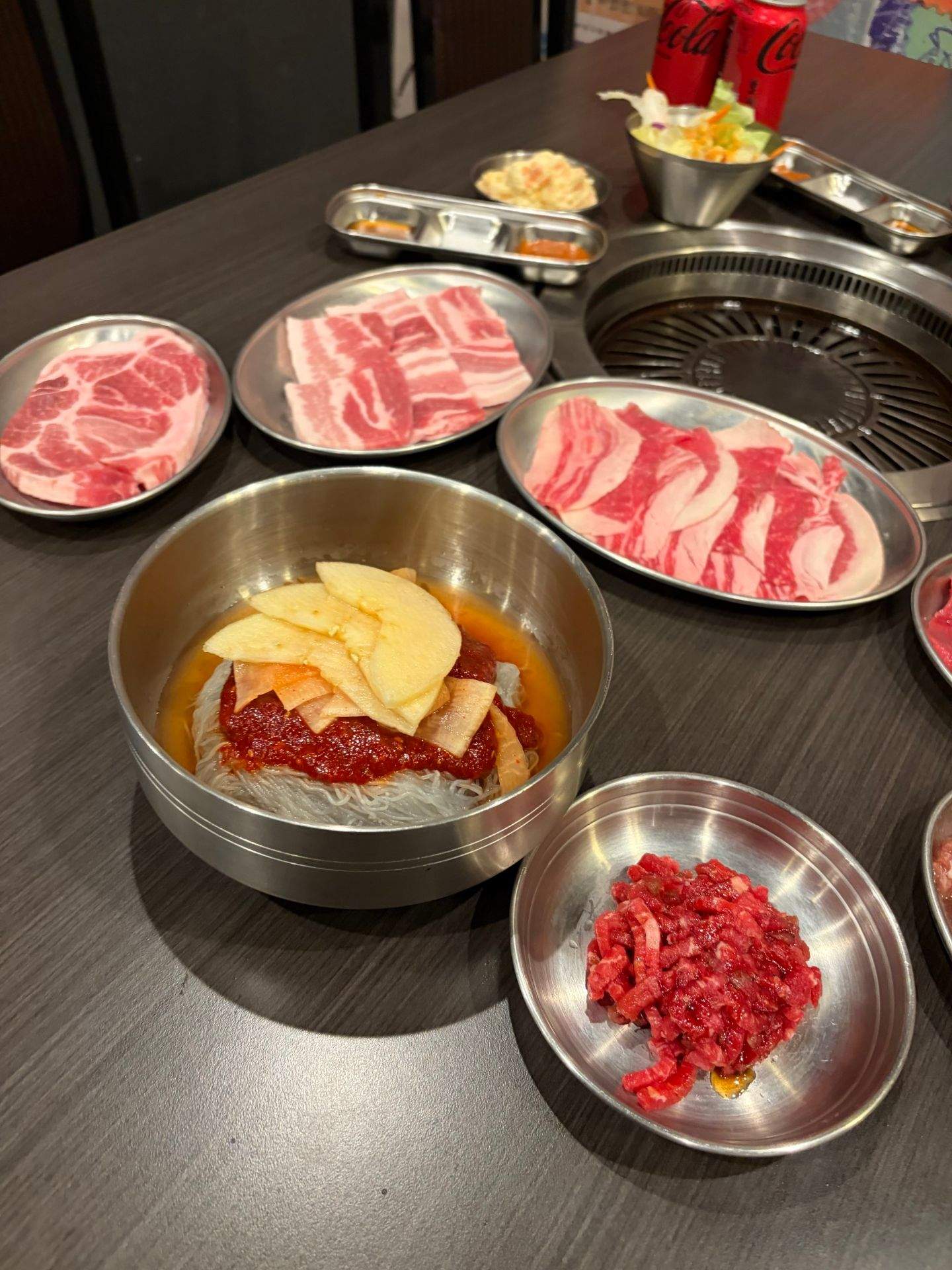 식탁 위에 고기, 야채, 소스가 담긴 접시가 놓여 있는 모습