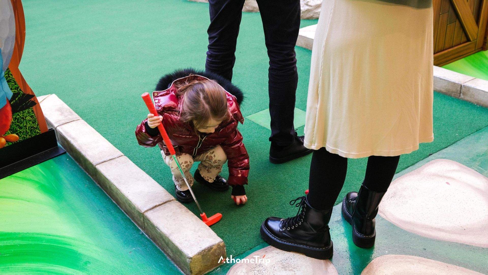 실내에서 아이와 사람이 골프 클럽을 사용하는 모습