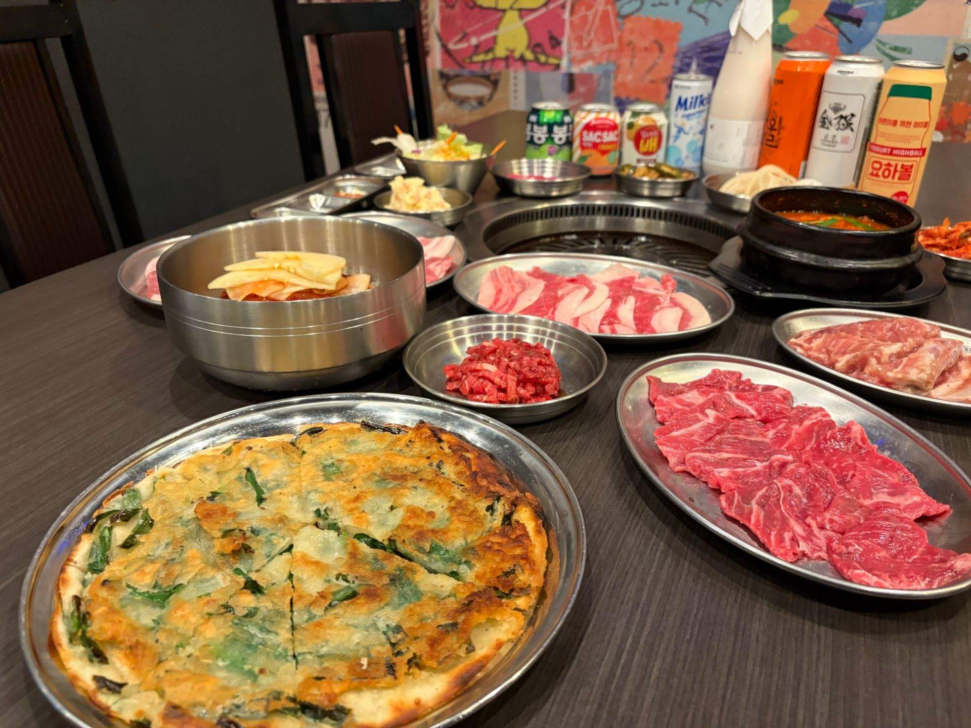 금색 계란 후라이, 고기 슬라이스, 채소 샐러드, 수프가 식탁 위에 놓인 장면
