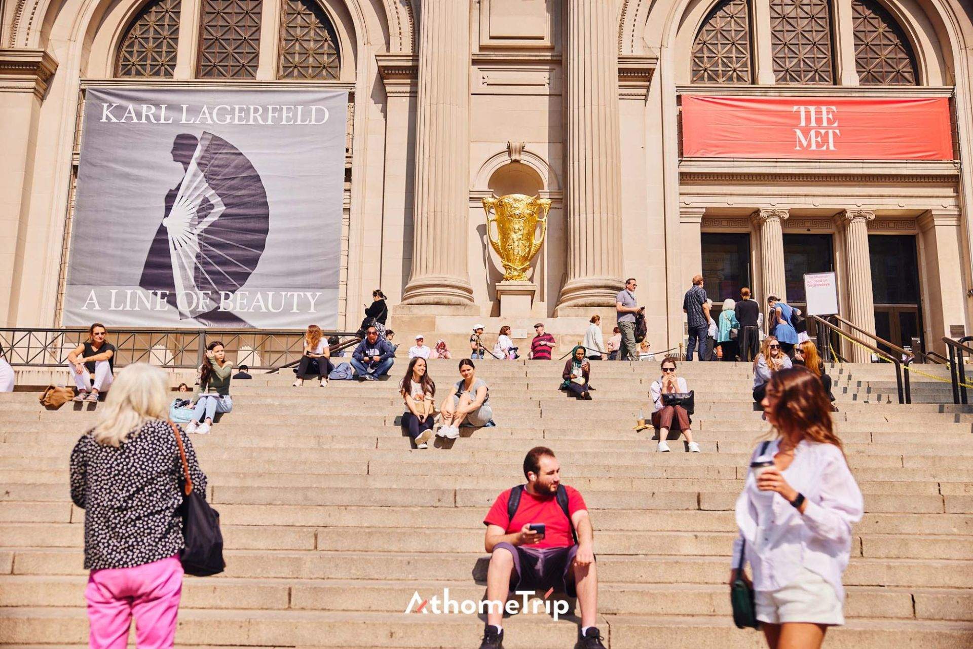 THE MET 문구가 적힌 건물 앞 계단과 사람들이 있는 실외 장면