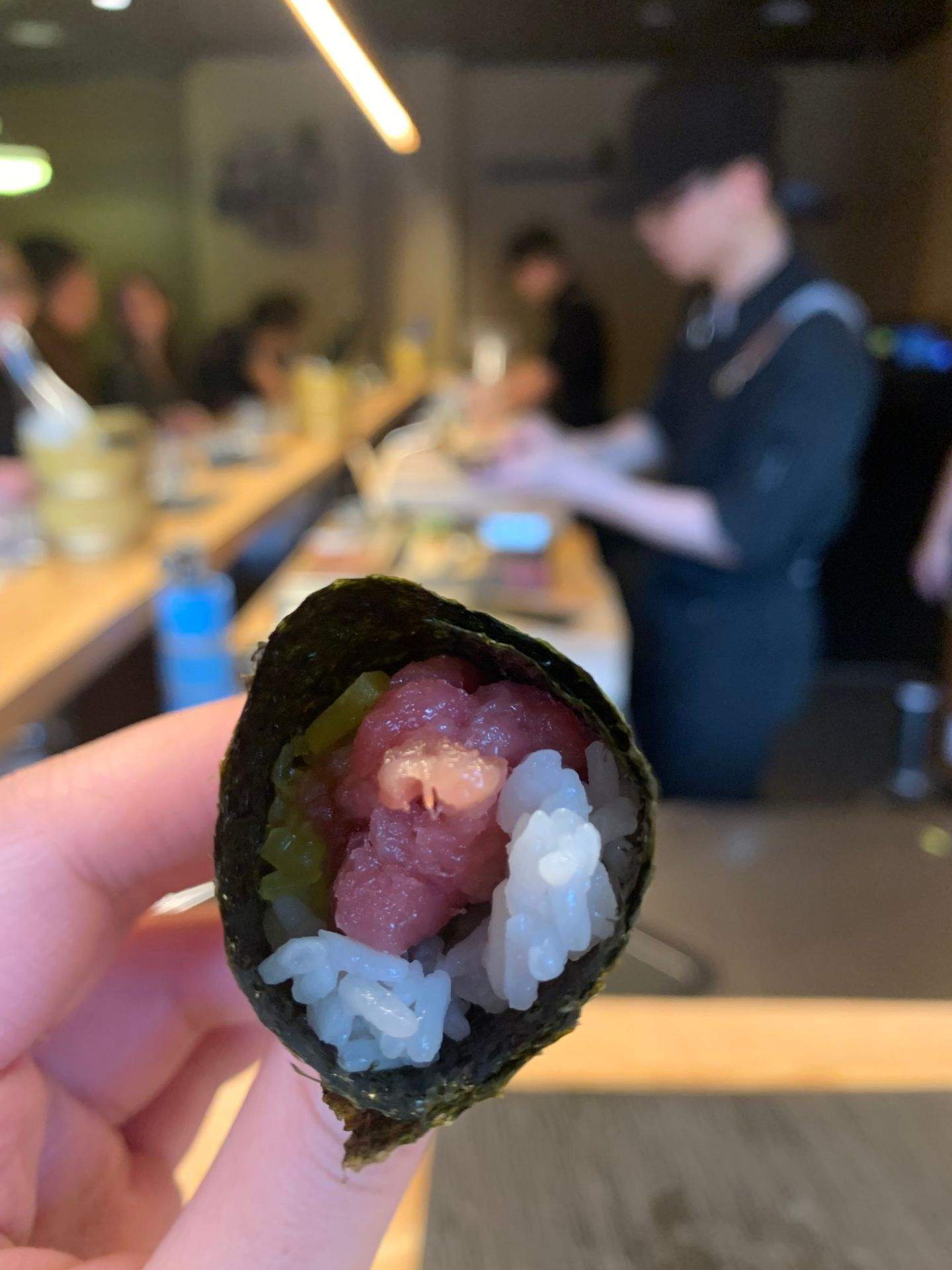손으로 들고 있는 김밥 안에 빨간색 생선과 흰 밥이 채워져 있는 모습