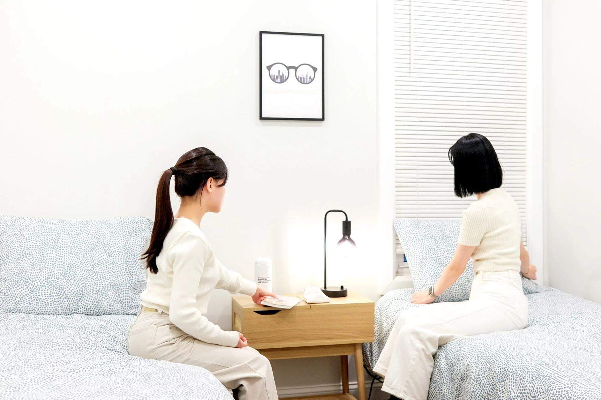실내에서 두 사람이 소파와 침대에 앉아 탁자 위의 물건을 보는 모습