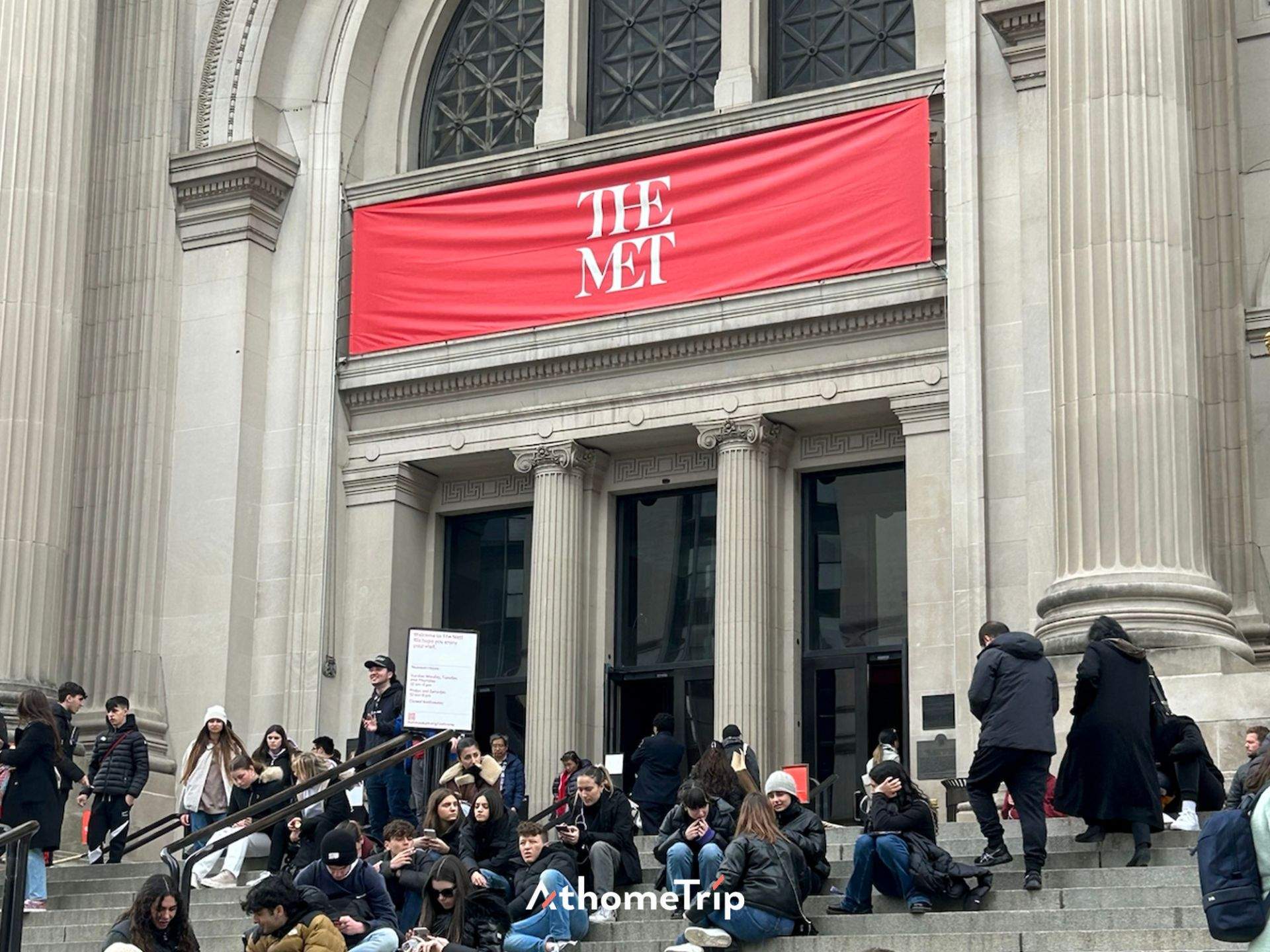 THE MET 문구가 보이는 대규모 건물 앞 계단에 사람들이 모여 있음