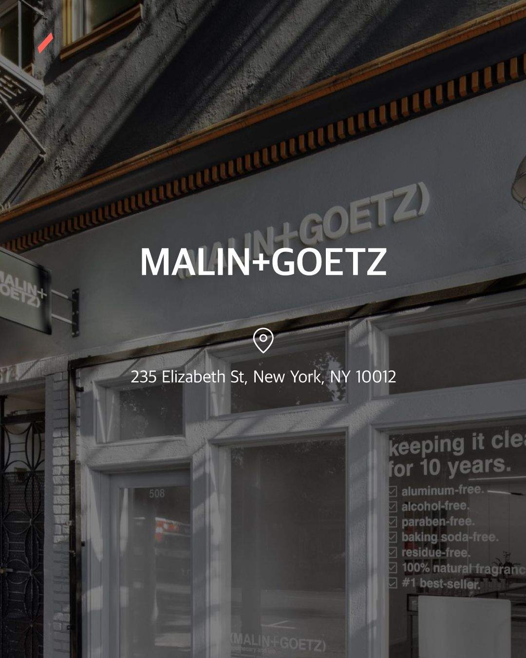 MALIN+GOETZ 문구가 적힌 간판과 건물의 유리창이 보이는 도시 장면