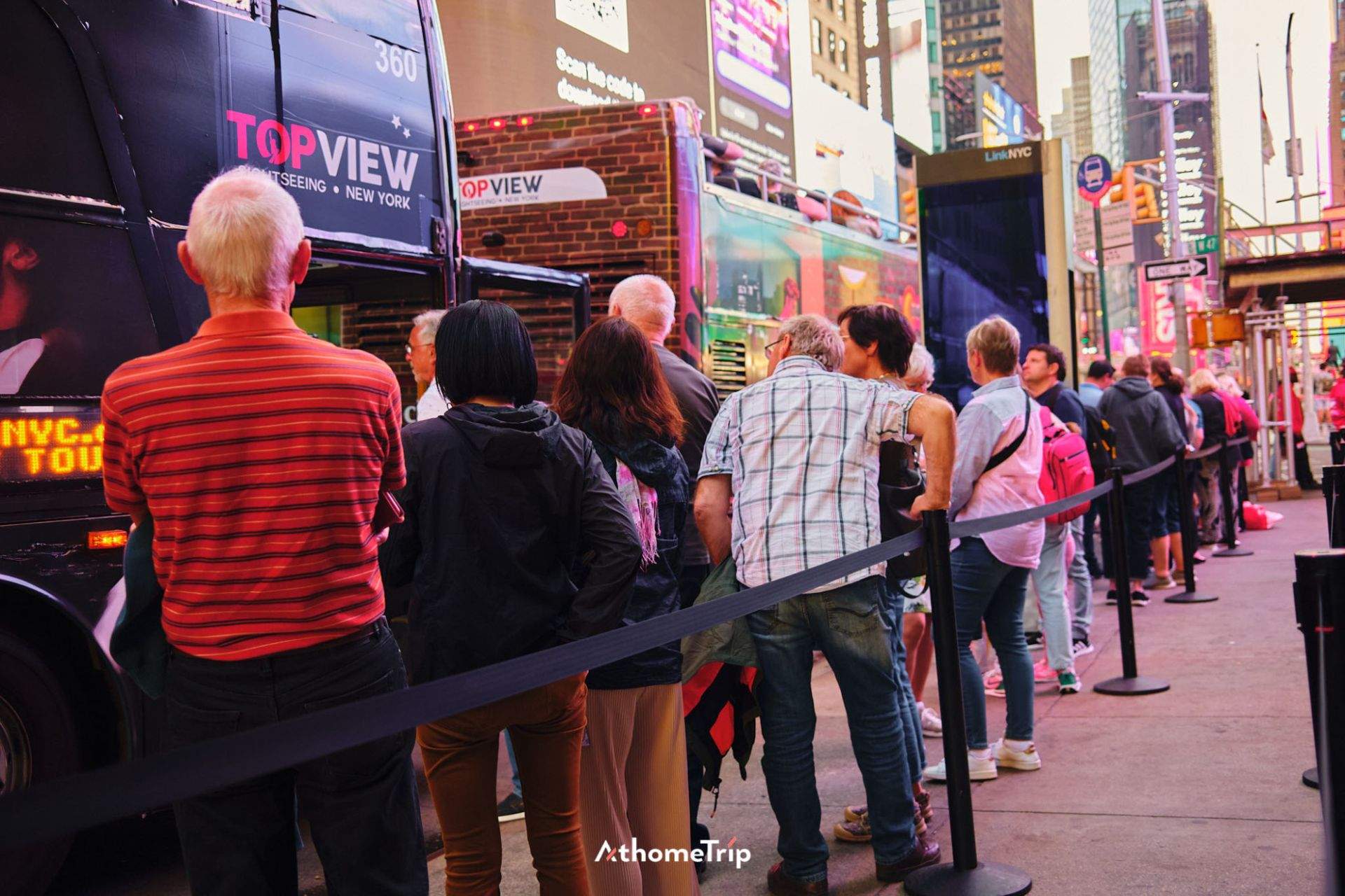 NEW YORK 문구가 보이는 건물 앞에서 버스를 기다리는 사람들