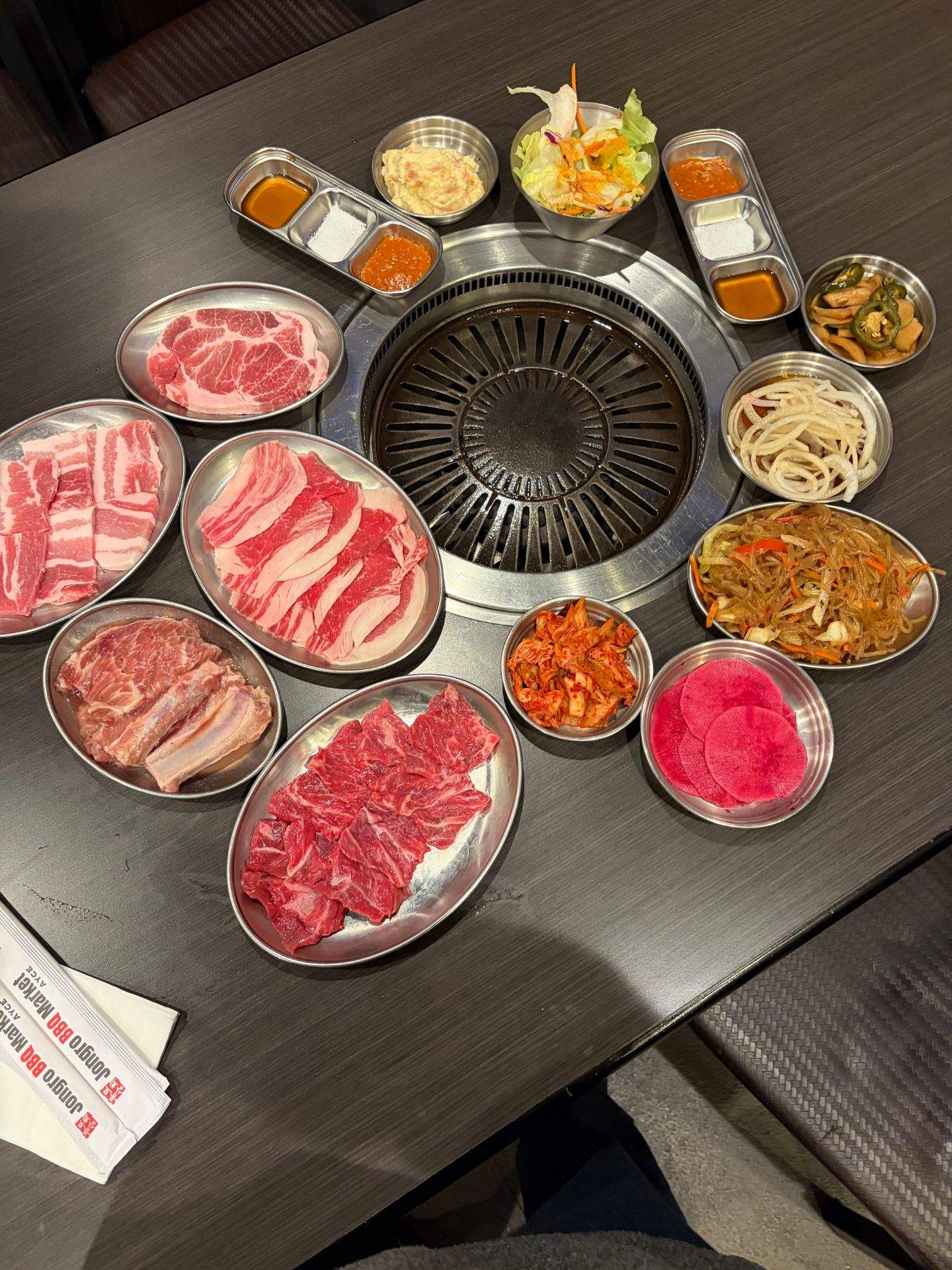 테이블 위에 여러 종류의 고기와 채소, 소스가 담긴 접시가 놓여 있는 사진