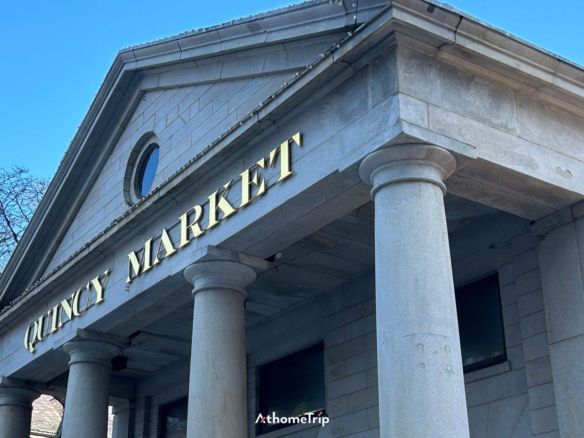 QUINCY MARKET 문구가 적힌 간판과 건물의 기둥이 보이는 실외 모습