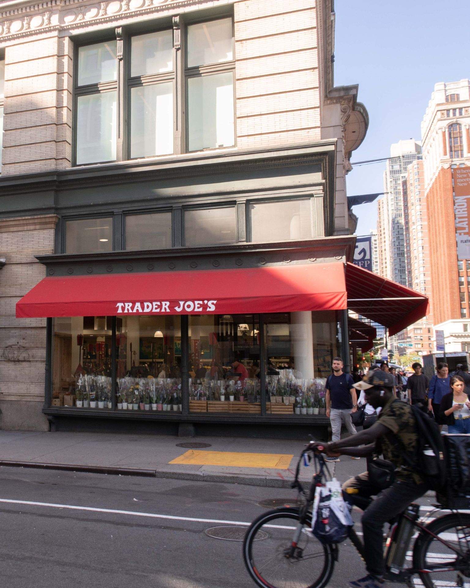 TRADER JOE'S 간판이 보이는 도시의 건물과 상점, 자전거가 있는 거리