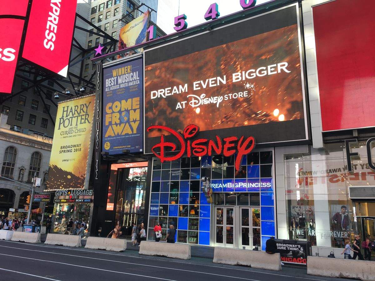 Disney 간판이 보이는 도심 거리의 건물과 주변 상점들